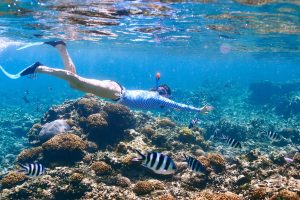 Woman with mask snorkeling in clear water